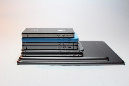 A stack of cell phones and tablets are stacked on top of each other.